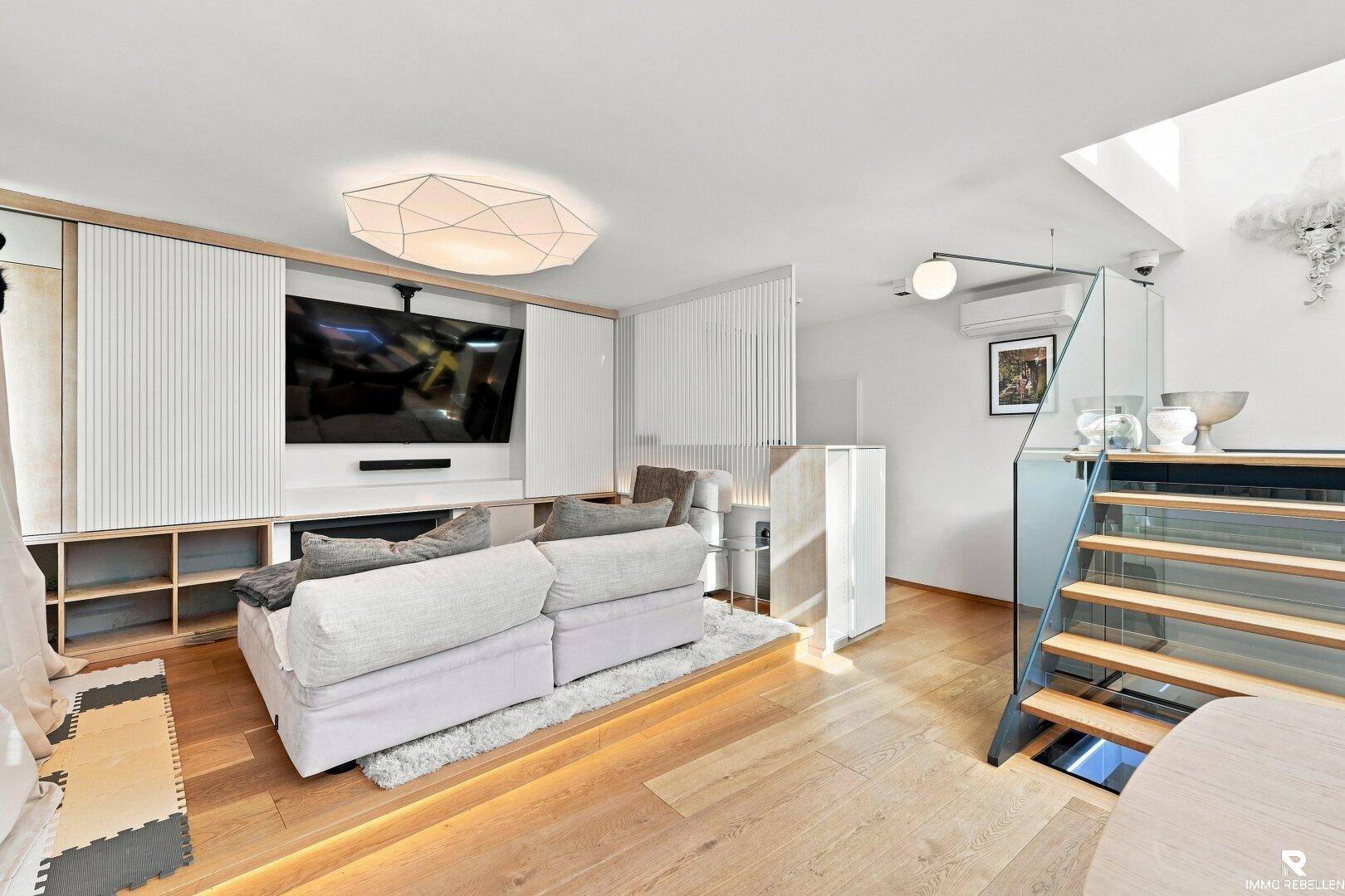 Gemütlicher Wohnbereich mit Sofa, integriertem TV-Möbel und Holzboden.