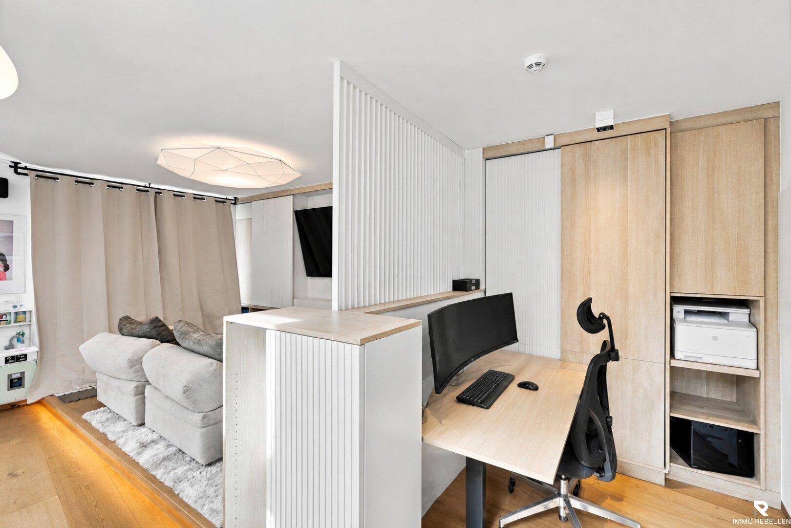 Funktionaler Arbeitsbereich mit Schreibtisch, Monitor und integrierten Holzschränken.