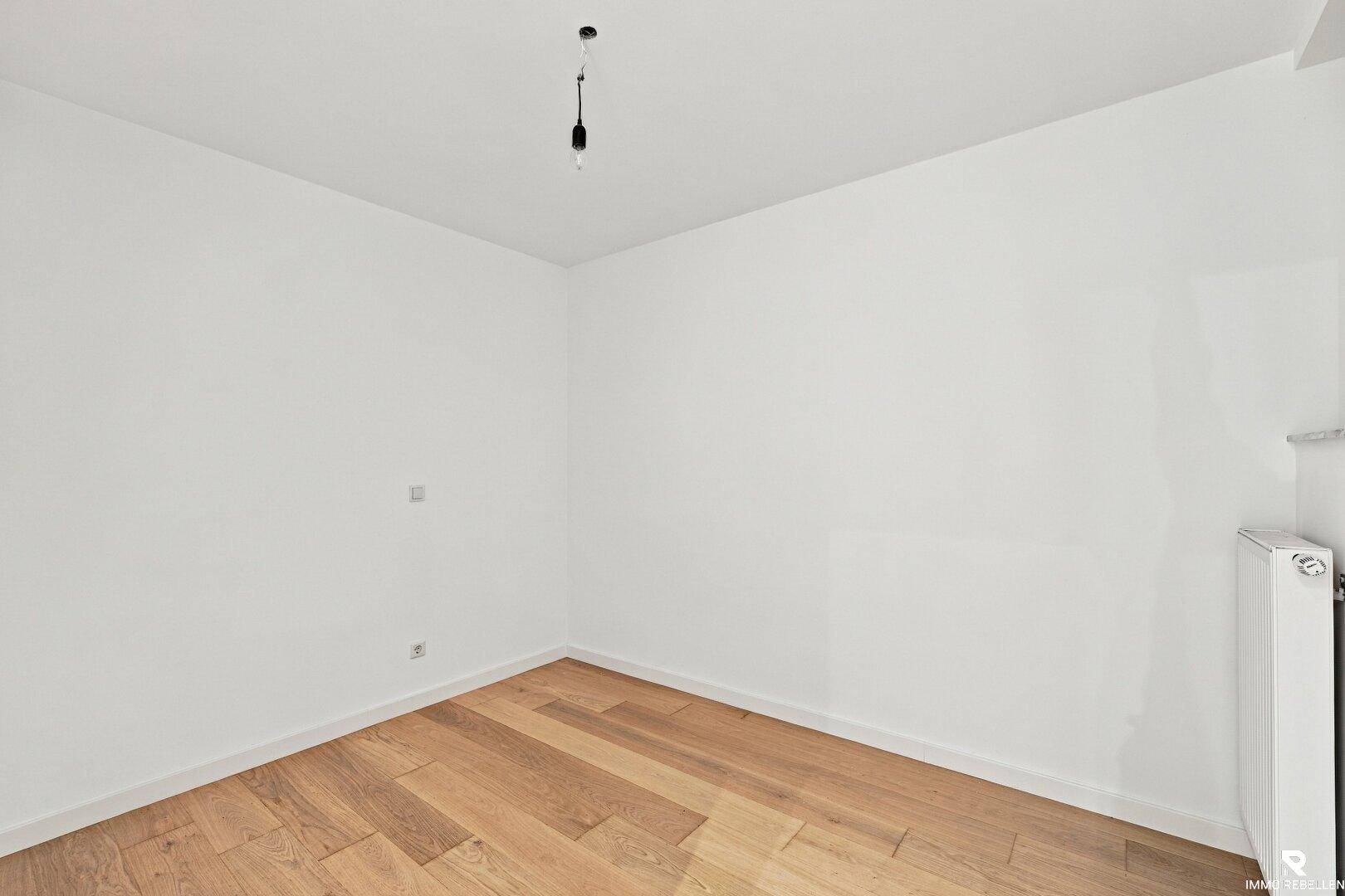 Leeres Zimmer mit Holzboden und weiß gestrichenen Wänden, vielseitig nutzbar als Büro oder Gästezimmer.