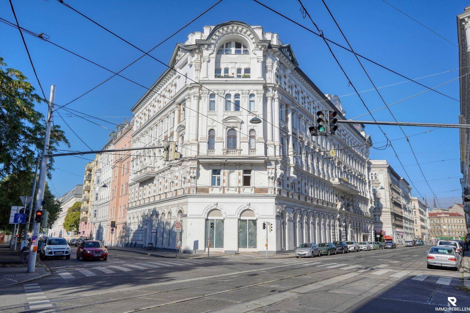 Historisches Eckgebäude mit eleganter Architektur an einer belebten Straßenkreuzung in der Stadt.