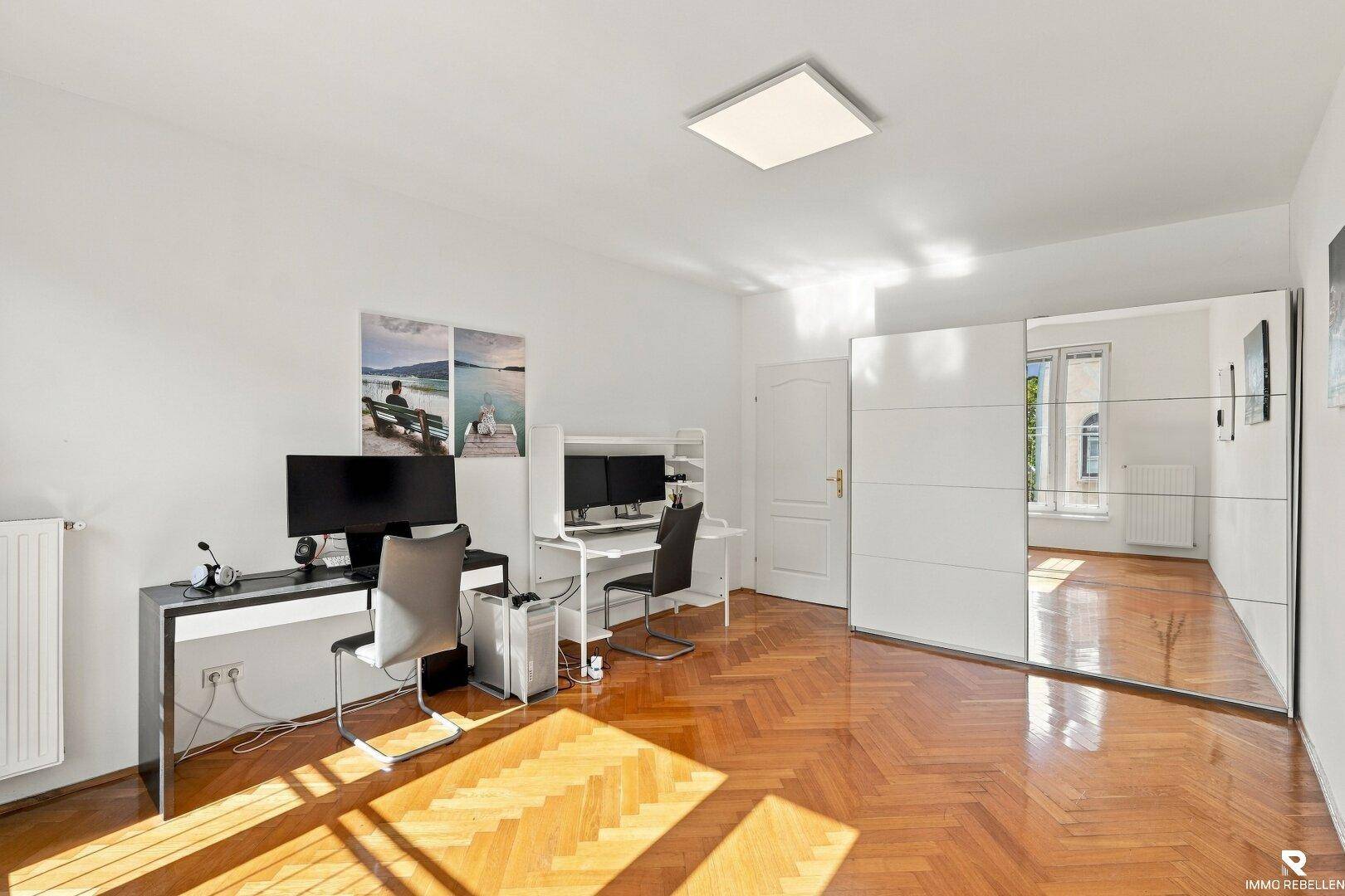 Arbeitszimmer mit Fischgrätparkett und großem Spiegelschrank, ideal für Home-Office.