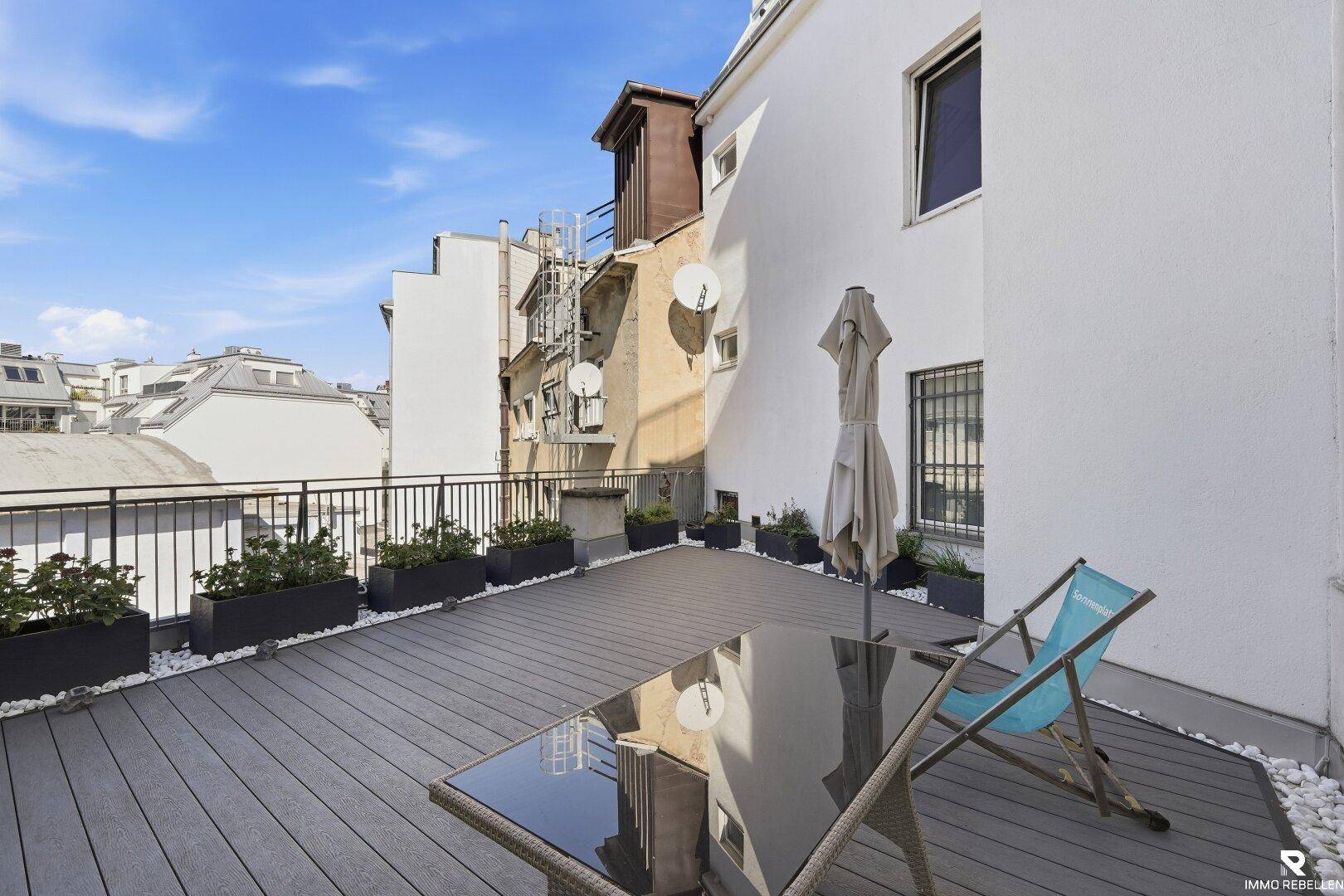 Sonnige Terrasse mit Ausblick auf die umliegenden Dächer und Gebäude der Stadt.