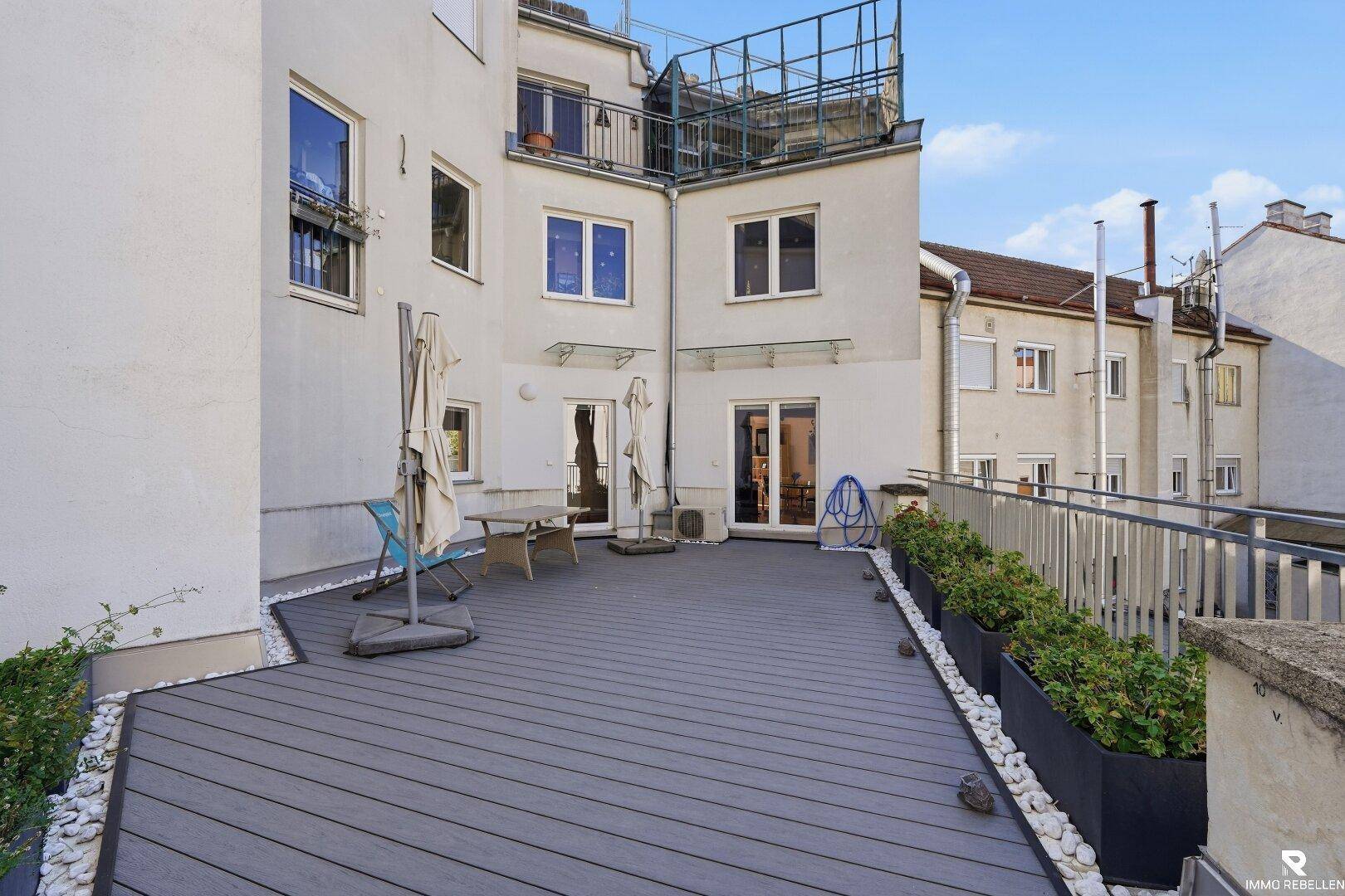 Geräumige Terrasse mit Holzoptik-Bodenbelag und Pflanzkübeln, bereit zur individuellen Gestaltung.