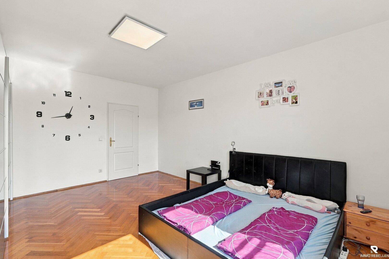 Schlafzimmer mit Fischgrätparkett, viel Platz und Zugang zu weiteren Räumen.