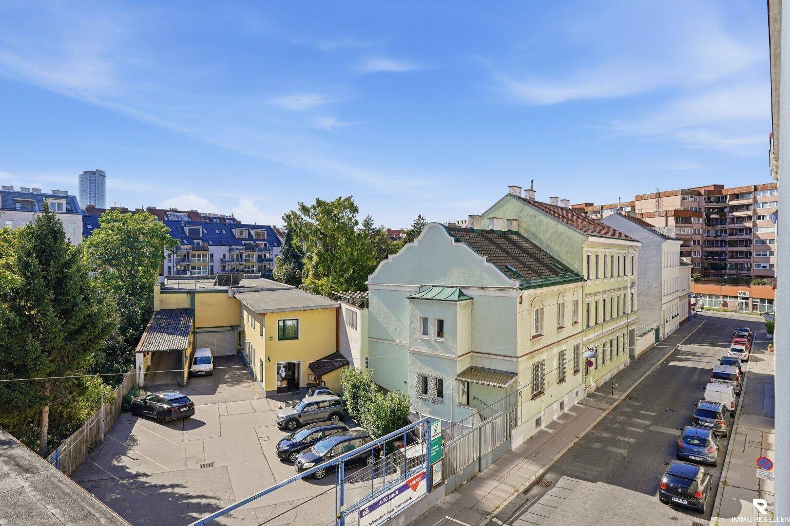 Blick von oben auf eine Wohnstraße mit parkenden Autos und umliegenden Gebäuden.