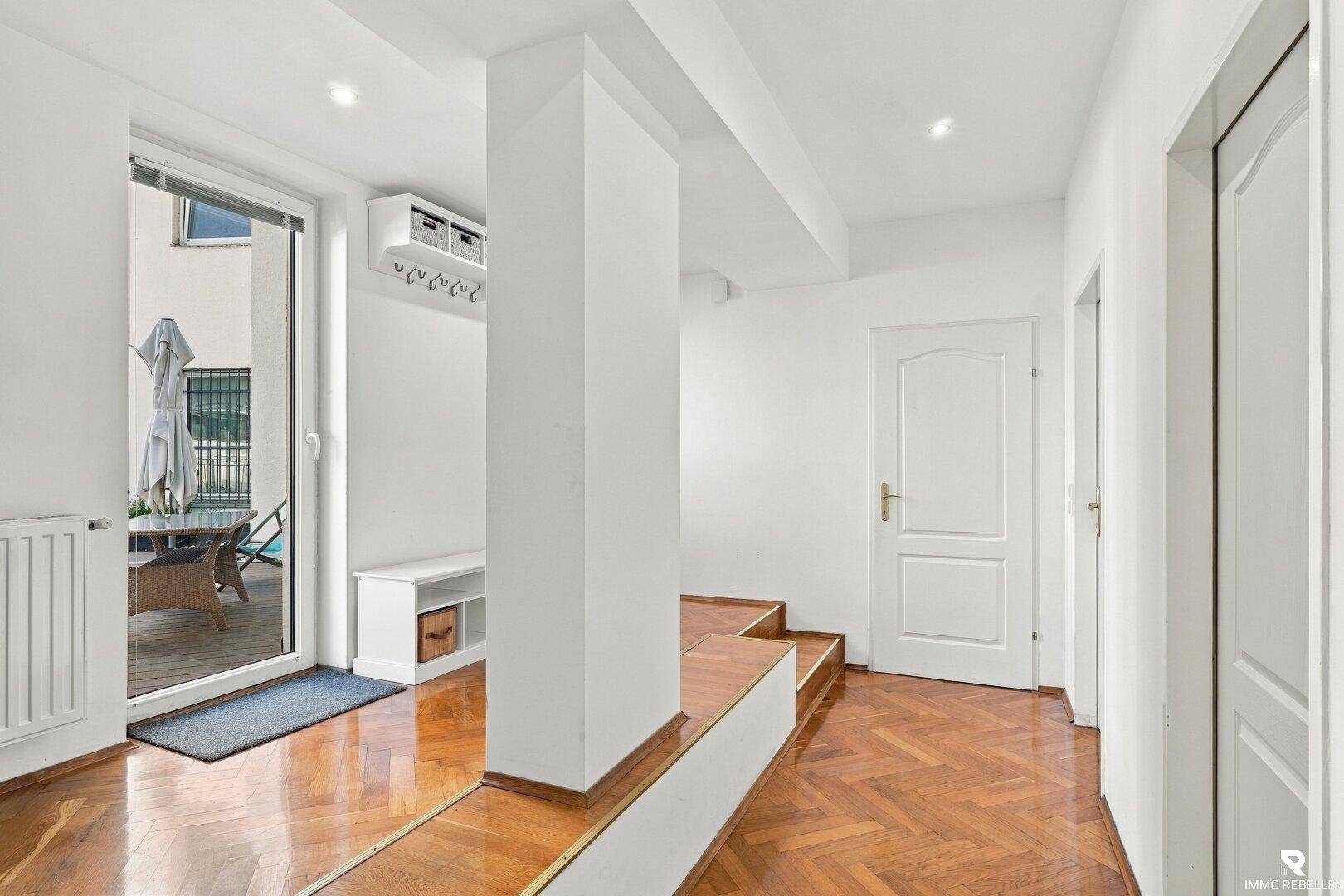 Eingangsbereich mit Fischgrätparkett, weißer Garderobe und Zugang zu den Wohnräumen.