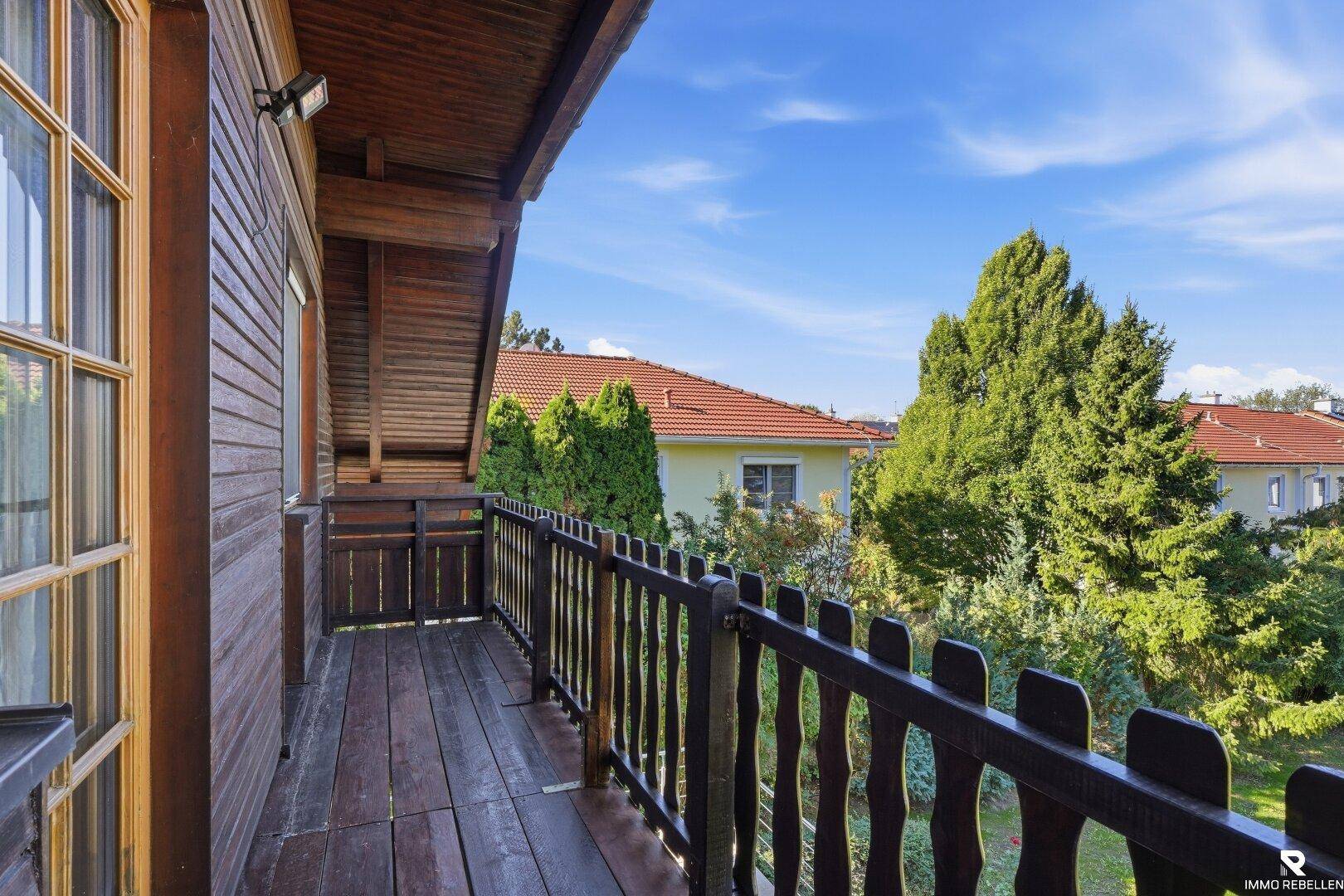 Holzverkleideter Balkon mit Geländer und Blick auf die umliegende grüne Landschaft.
