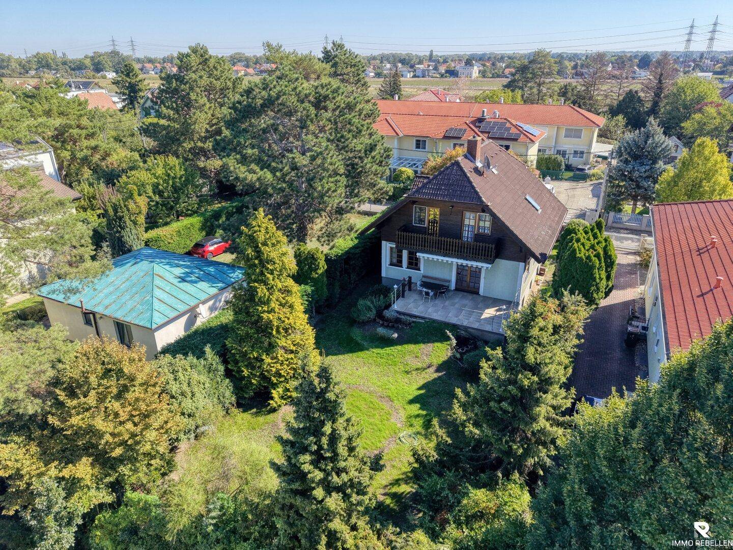 Luftaufnahme des Anwesens mit großem Garten und umliegender Wohnbebauung unter klarem Himmel.