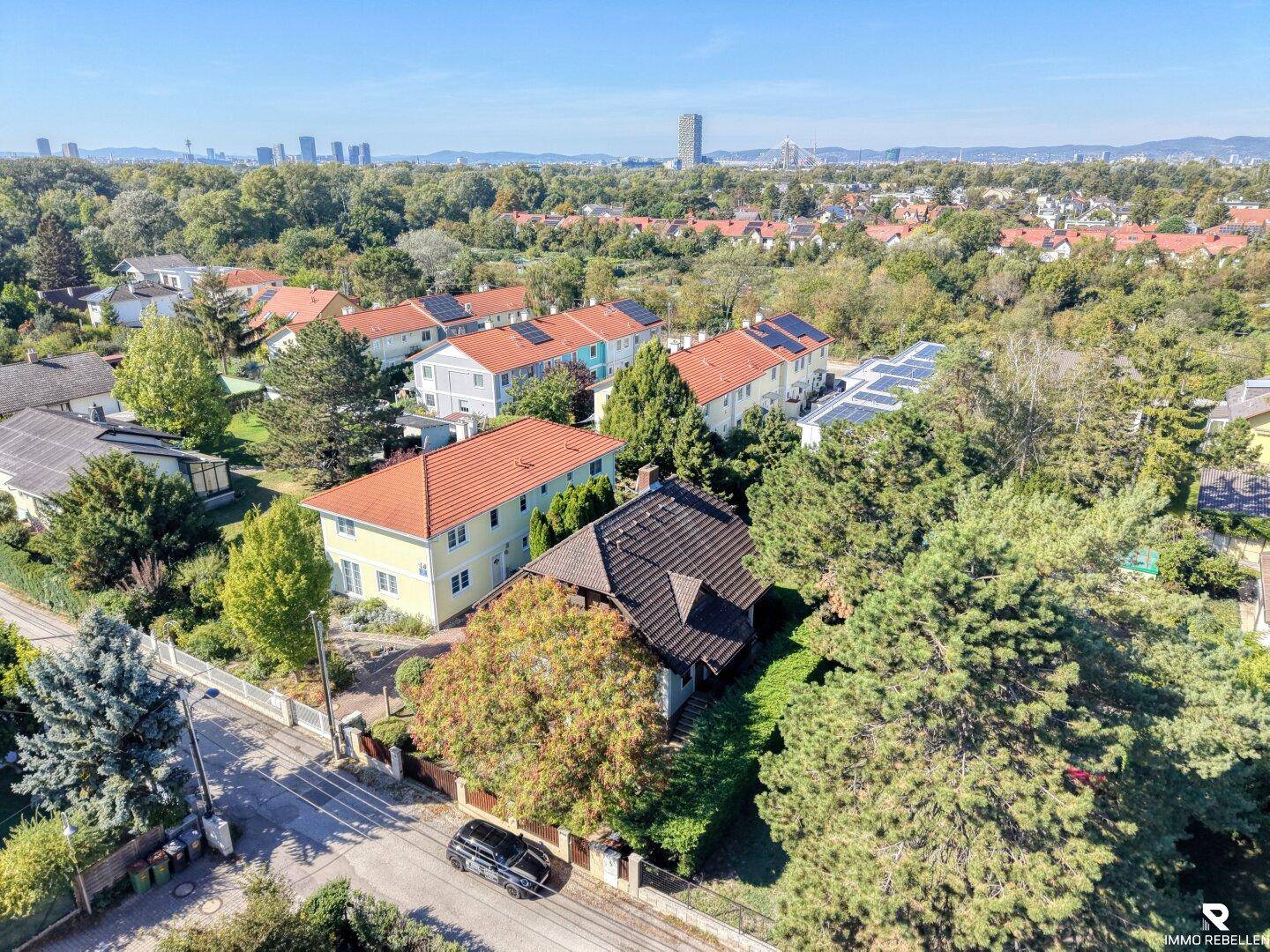 Weitläufige Luftaufnahme der Wohngegend mit vielen Bäumen und Blick auf die Stadt in der Ferne.