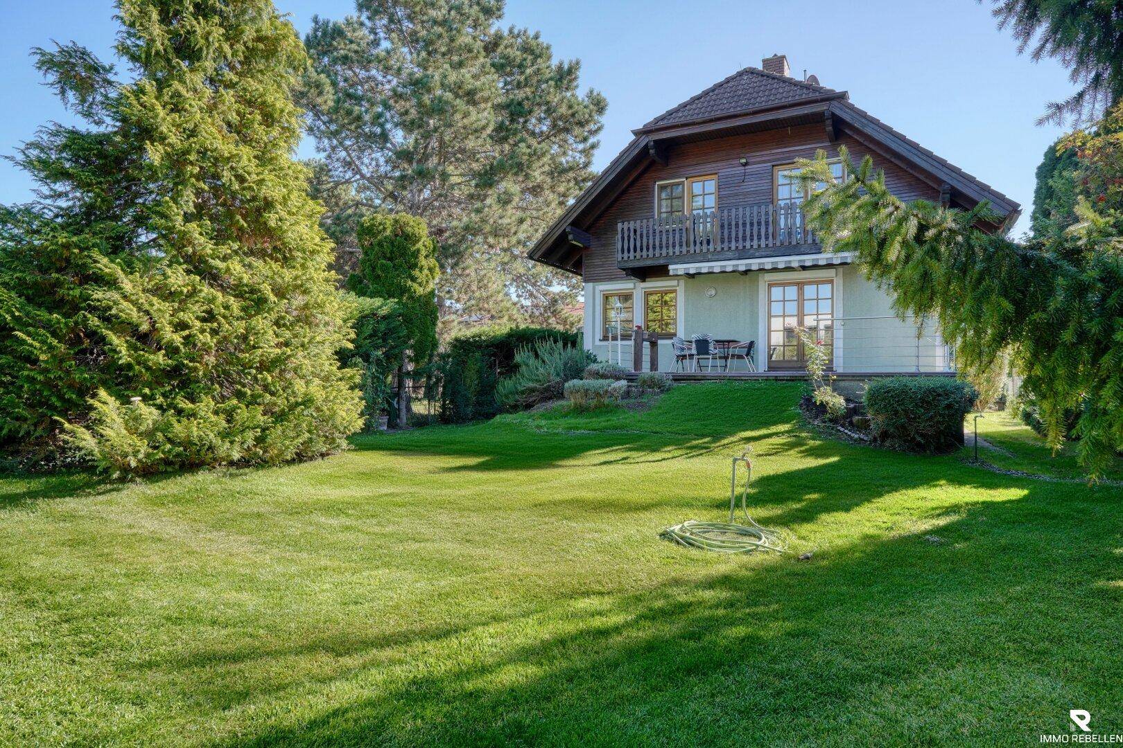 Großer, gepflegter Rasenbereich hinter dem Haus mit Terrasse und Balkon im Obergeschoss.