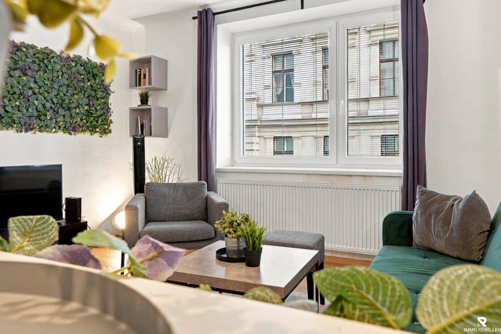 Heller Wohnbereich mit Sessel, Holzboden und Blick auf die Straße.