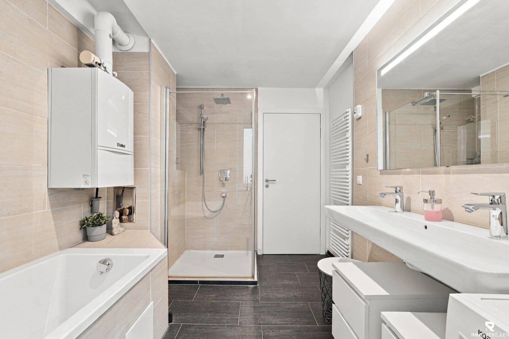 Helles Badezimmer mit Doppelwaschbecken, Dusche und Badewanne.