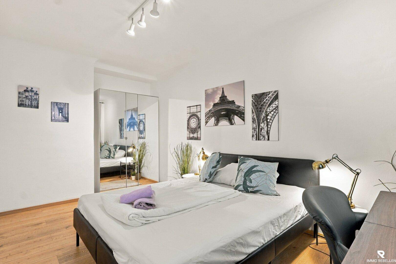 Schlafzimmer mit Doppelbett, Spiegelschrank und Holzboden.