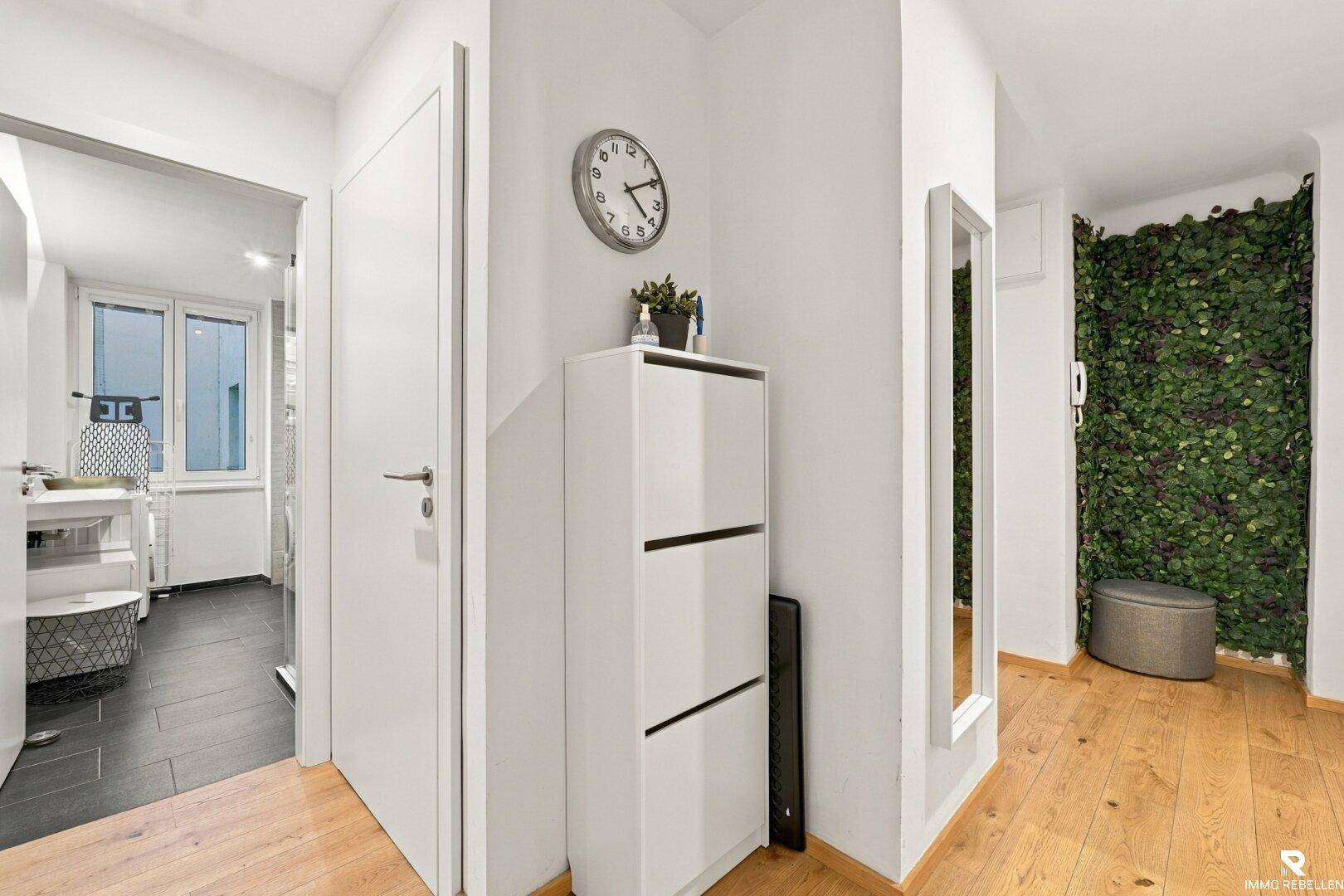 Flur mit Holzboden, Spiegel und Schuhschrank.