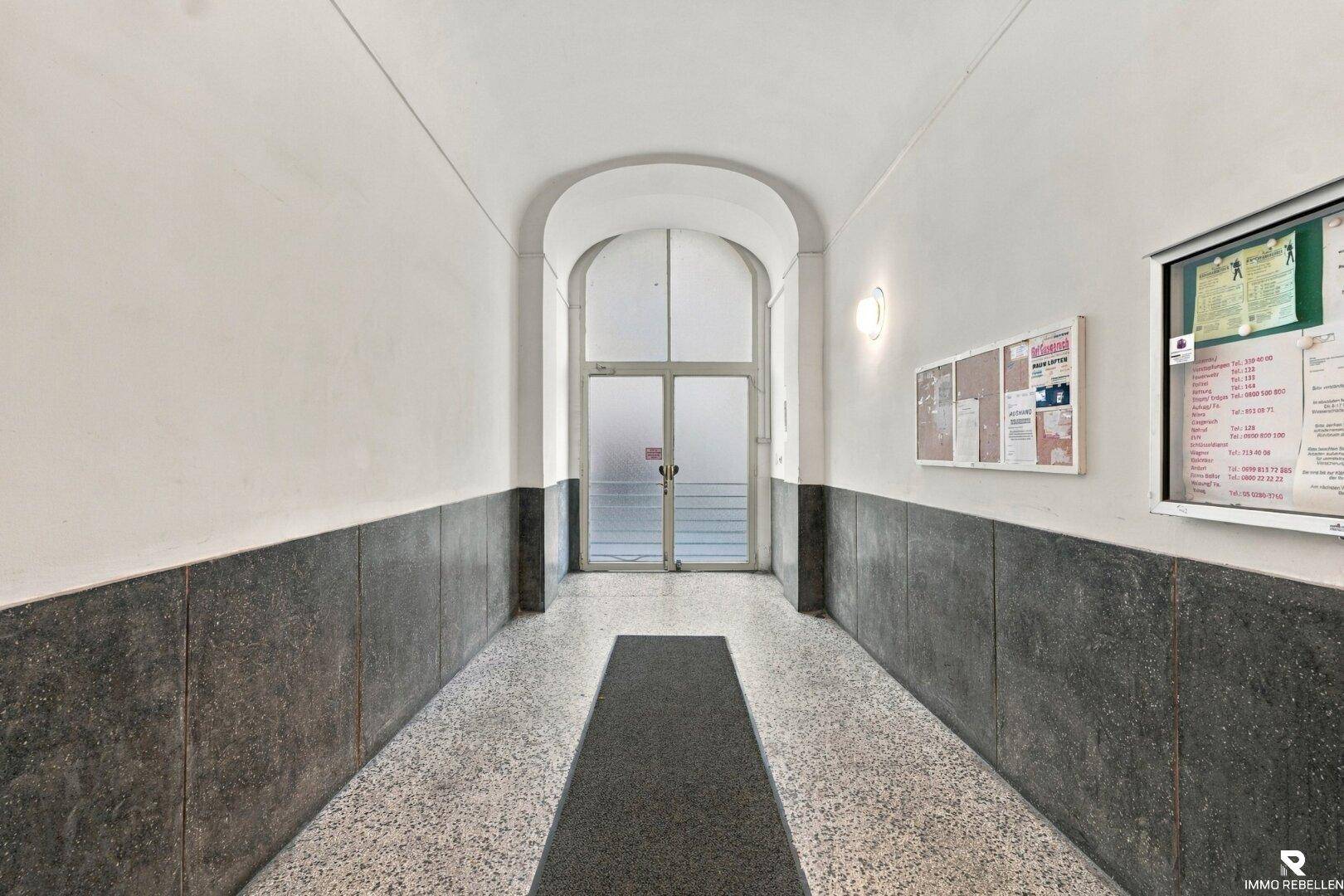Eingangsbereich eines Altbaus mit gewölbter Decke und Terrazzoboden.