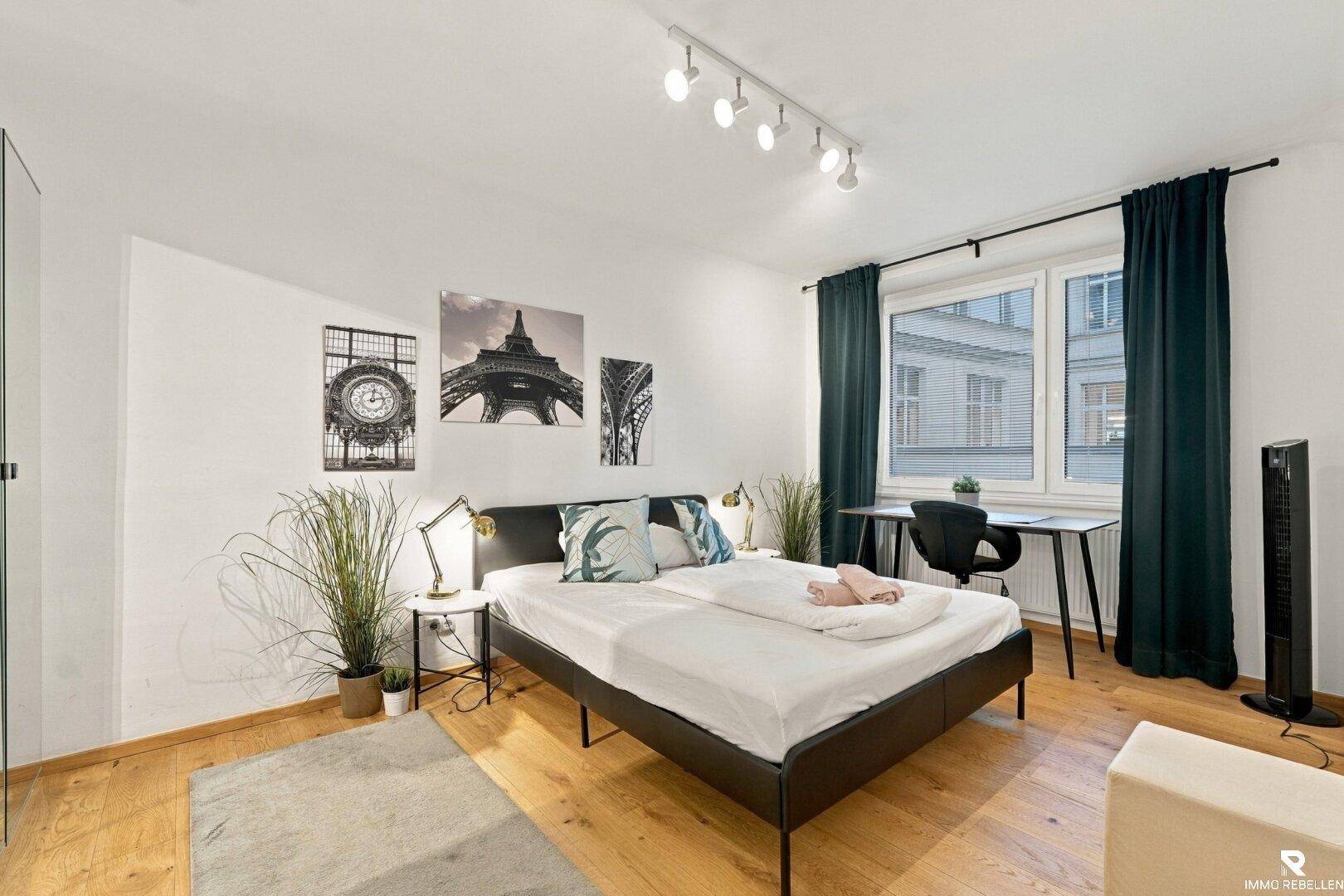 Modern eingerichtetes Schlafzimmer mit Doppelbett, Holzboden und Schreibtisch.