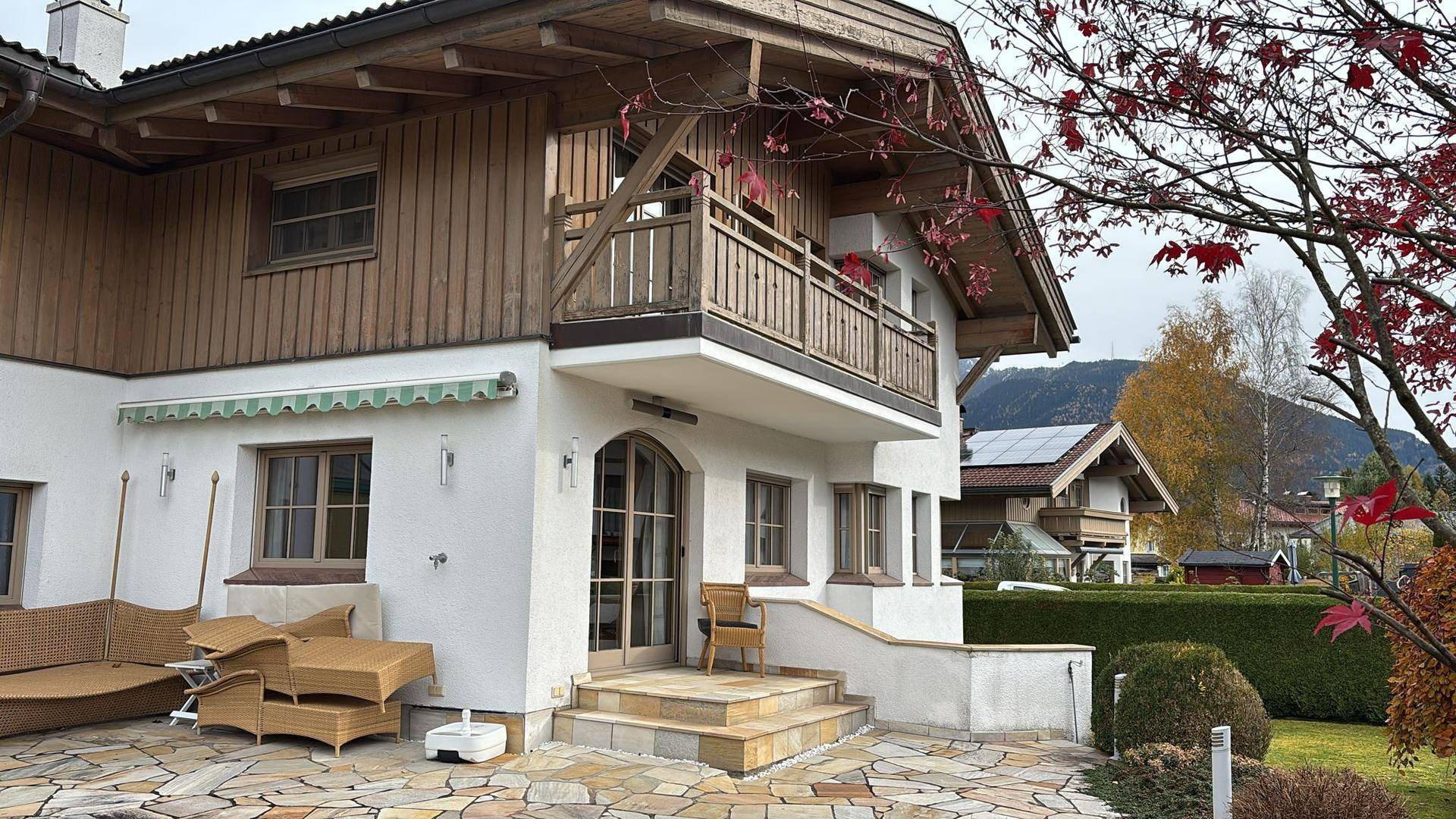 Seitliche Ansicht des Hauses mit Terrasse, Balkon und Blick auf die umliegende Berglandschaft.