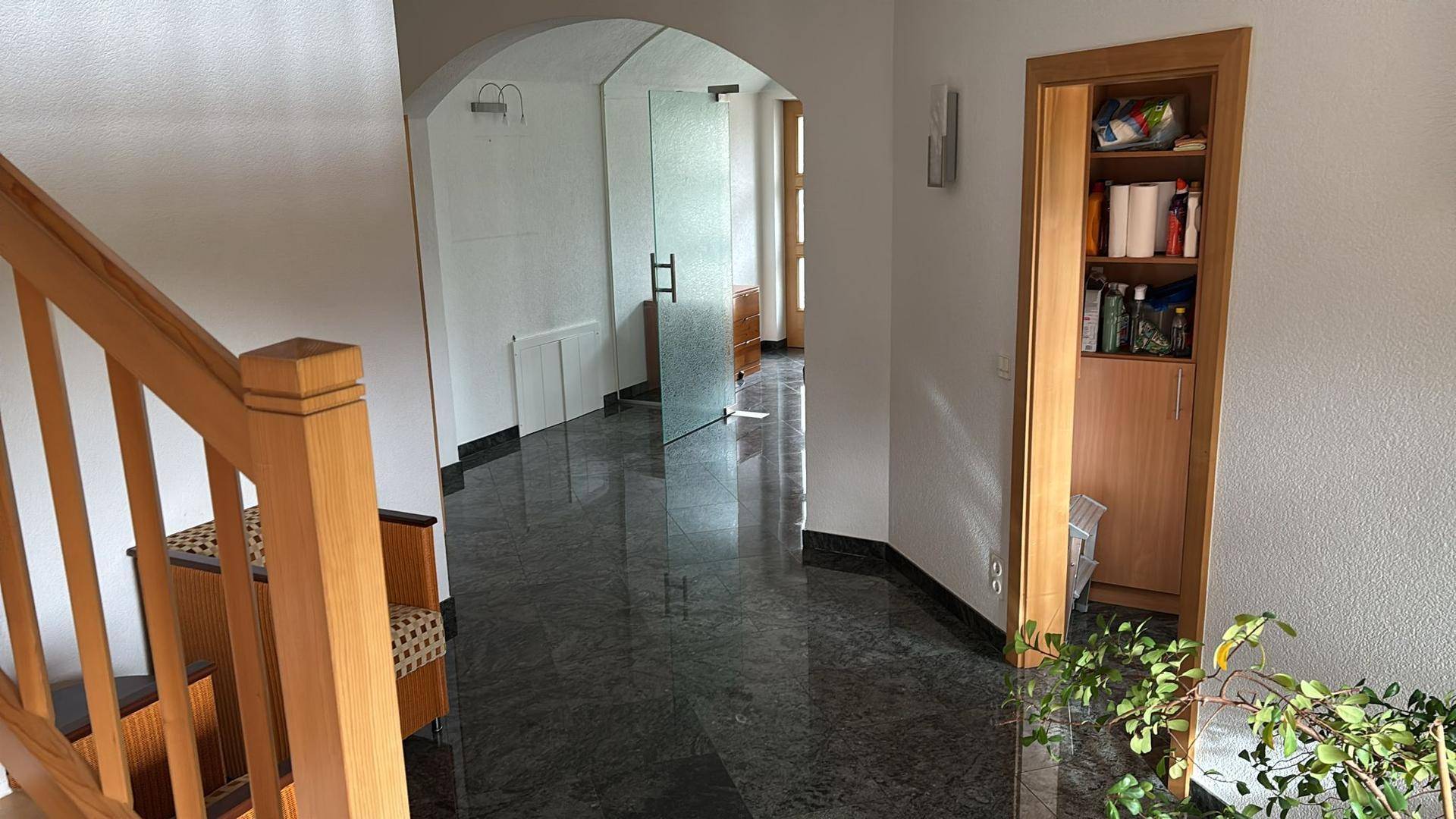Heller Flur mit Marmorboden, Holztreppe und Glastür, die zu weiteren Räumen führt.