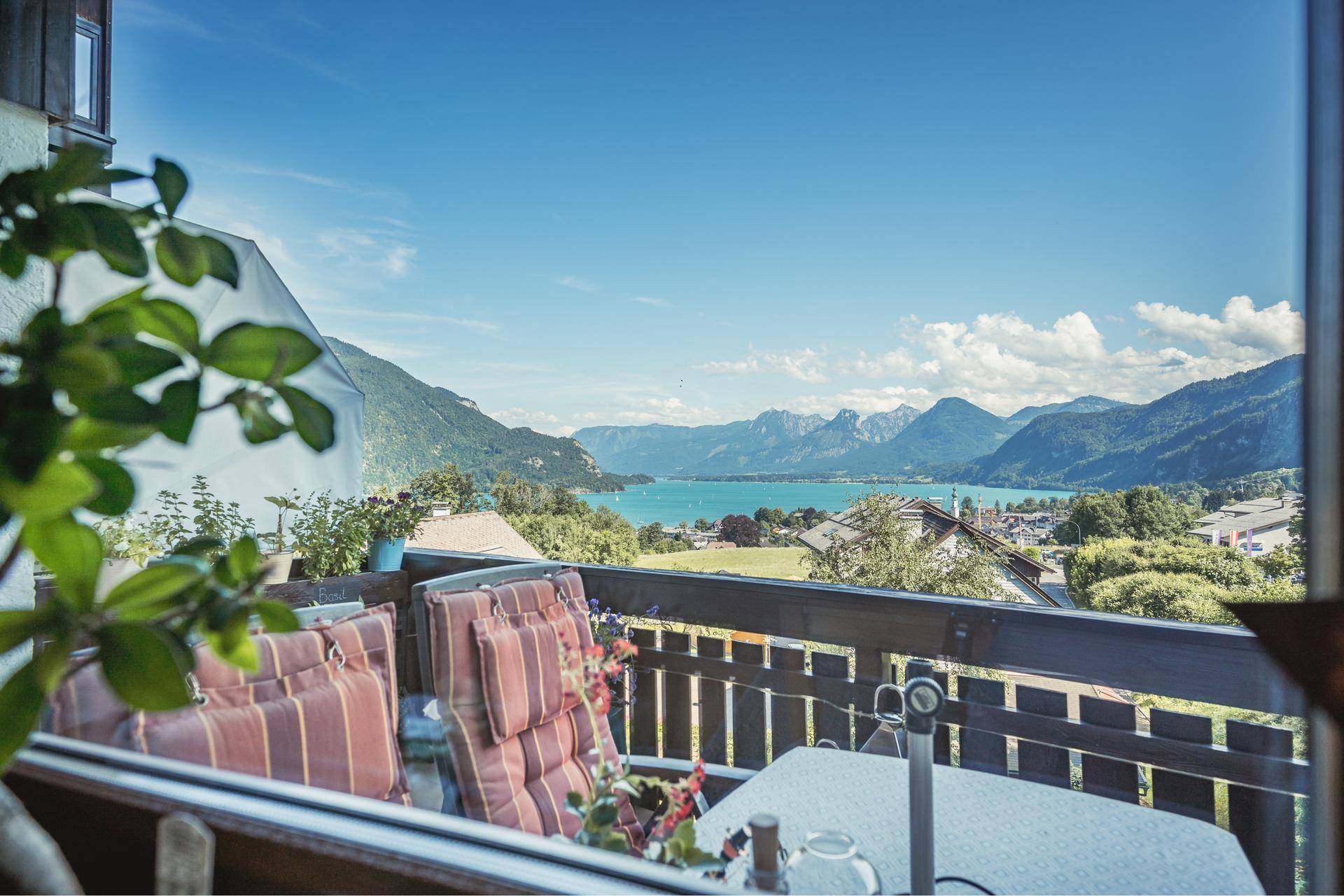 Gemütlicher Balkon mit bequemen Sitzkissen und weitem Panoramablick über den See und die Berge.