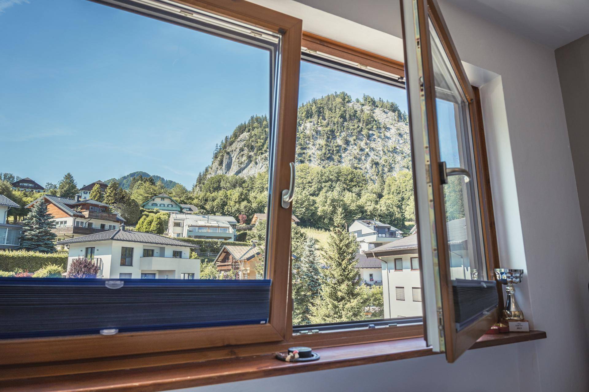 Weitblick aus dem Fenster auf eine malerische Berglandschaft und die umliegende Siedlung.