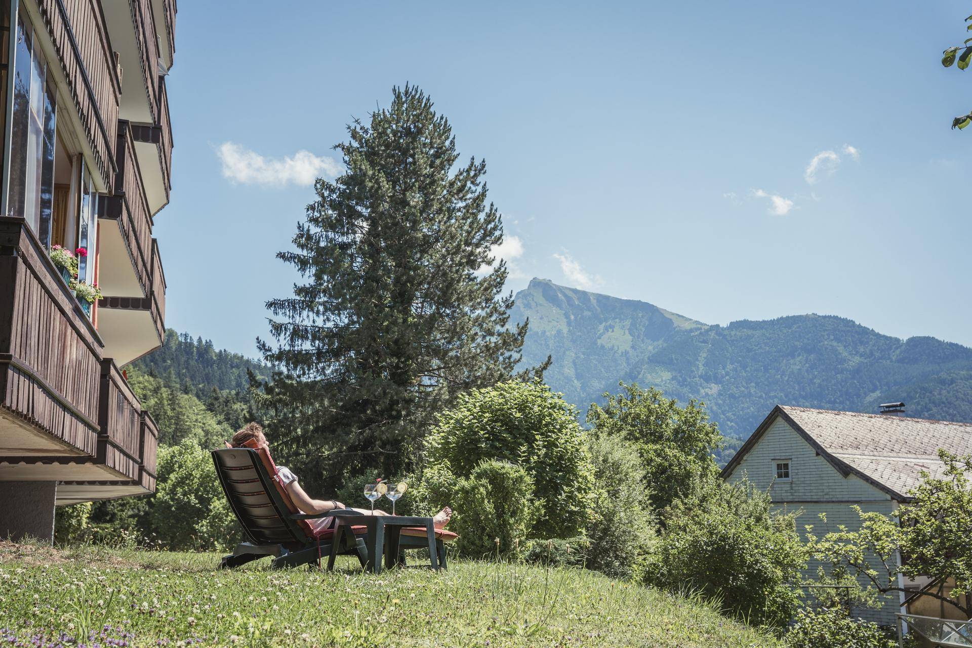 Entspannter Sitzbereich im Garten mit Liegestuhl und herrlichem Bergblick.