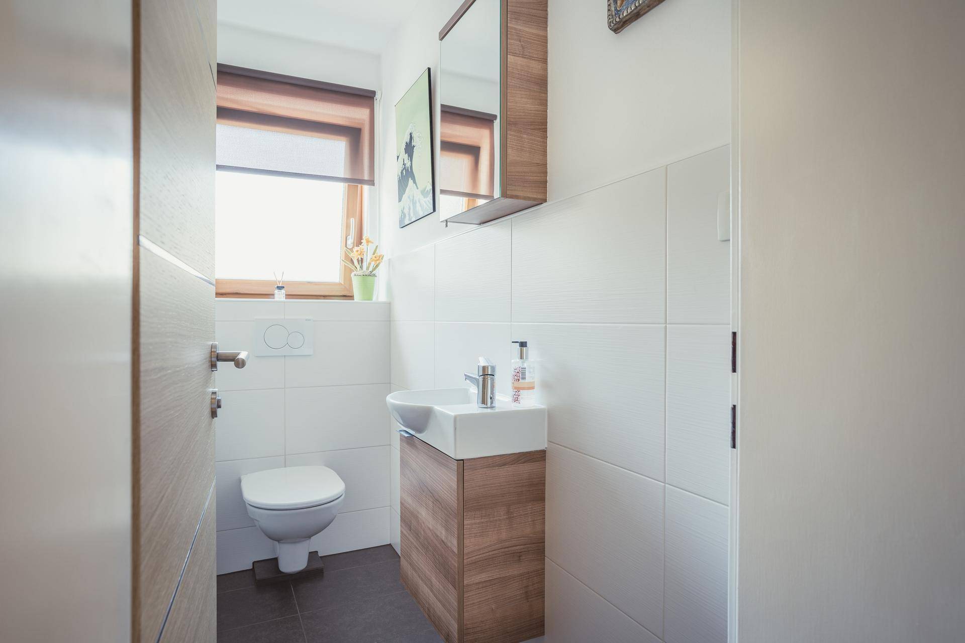 Modernes Gäste-WC mit Fenster, wandhängender Toilette und kleinem Waschbecken.