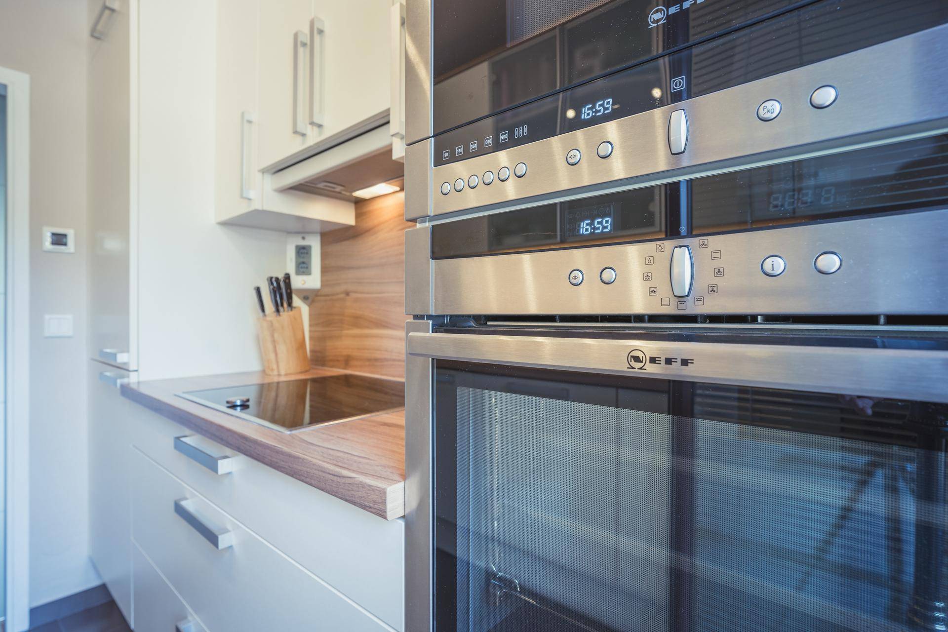 Detailansicht der modernen Küche mit Backofen, Mikrowelle und Induktionskochfeld.