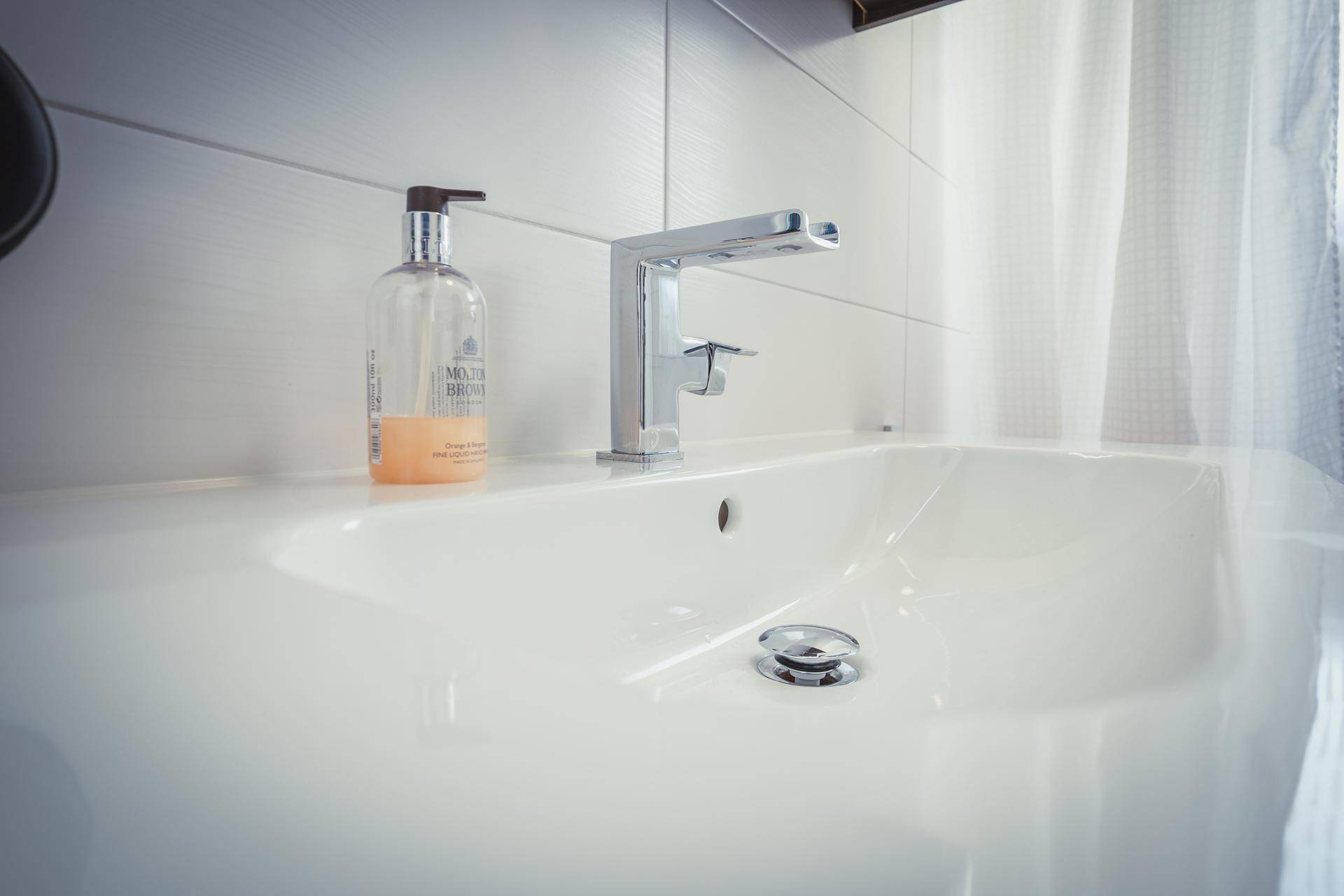 Detailaufnahme des modernen Waschbeckens mit elegantem Wasserhahn und Seifenspender.