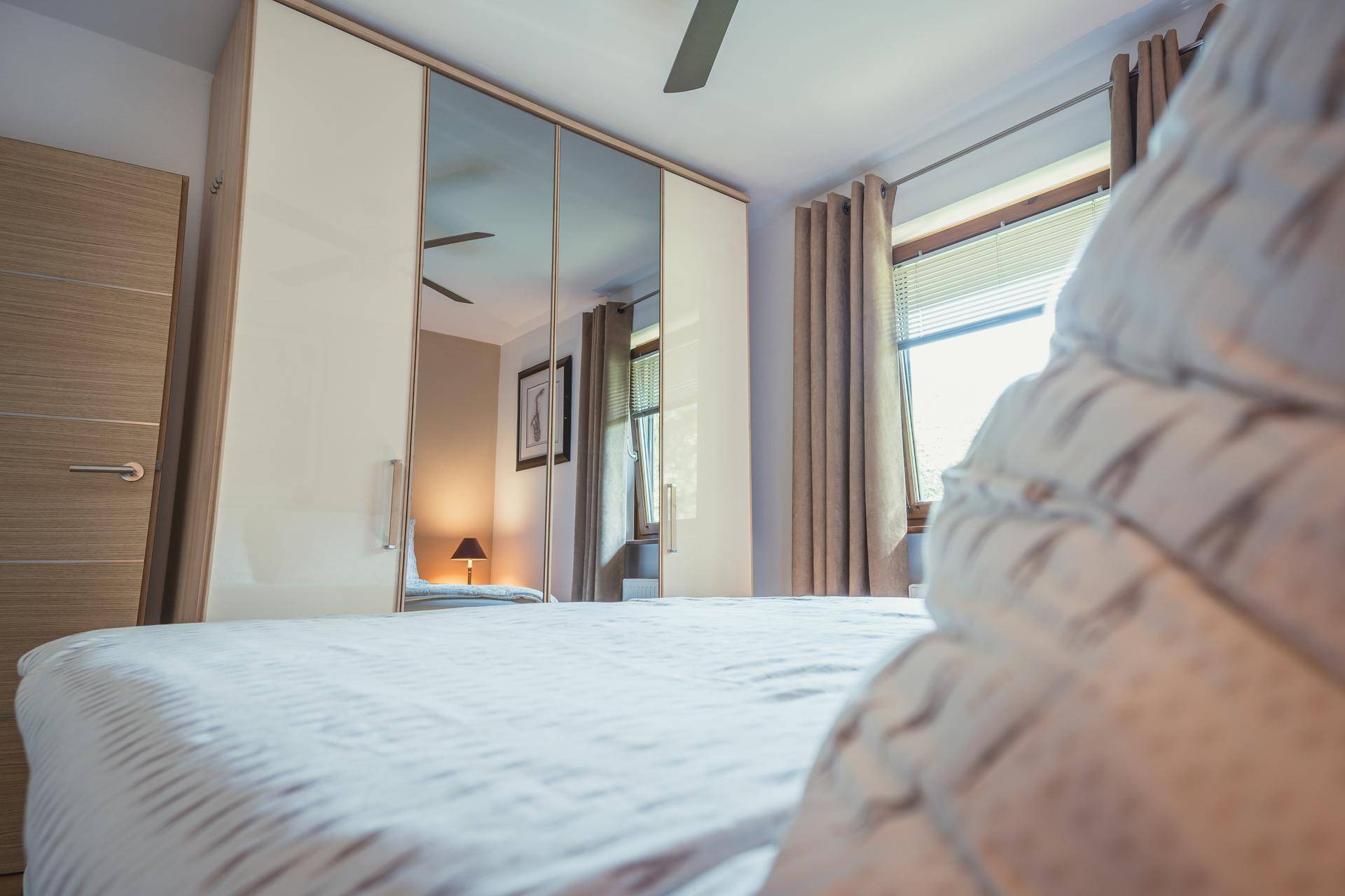 Schlafzimmer mit großem Spiegelschrank, Doppelbett und hellem Holzboden.