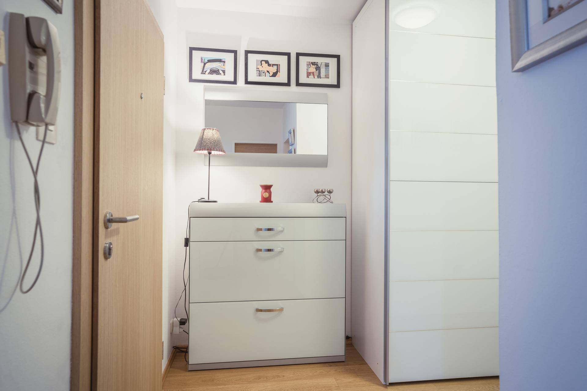 Flur mit modernem Schuhschrank, Spiegel und Holzboden.