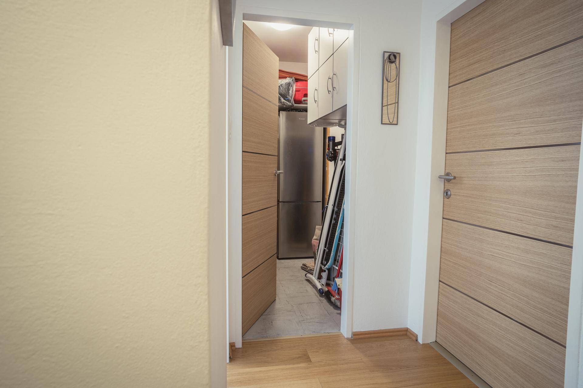 Flur mit Zugang zu einem praktischen Abstellraum, ausgestattet mit einem Kühlschrank.