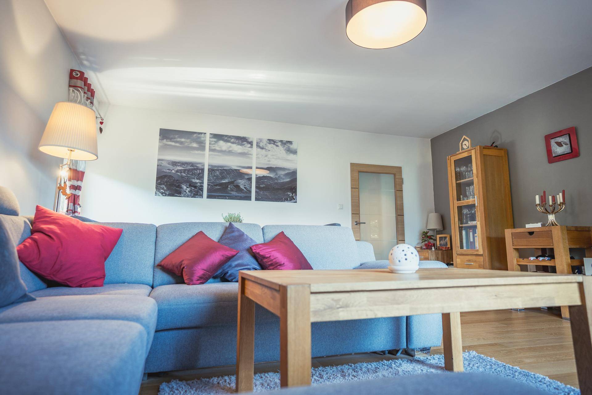 Helles Wohnzimmer mit bequemer Couch, Holztisch und moderner Wanddekoration.