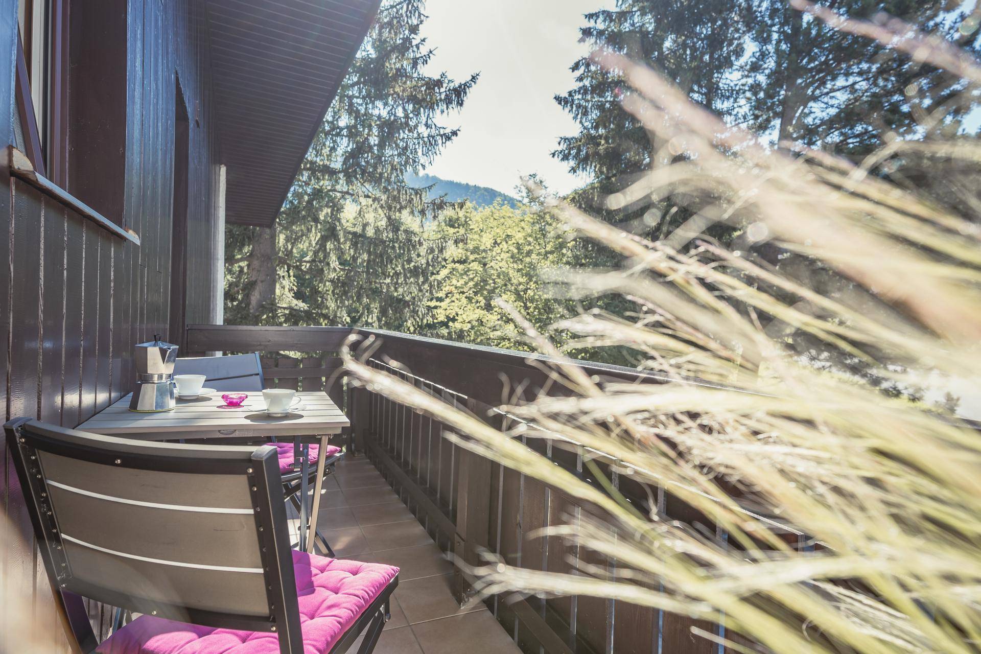 Balkon mit Sitzgelegenheiten und Blick auf die üppige Vegetation und die Berge.