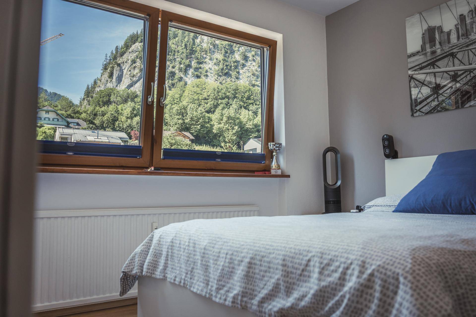 Gemütliches Schlafzimmer mit Bergblick und Holzelementen am Fenster, ausgestattet mit einem bequemen Bett.