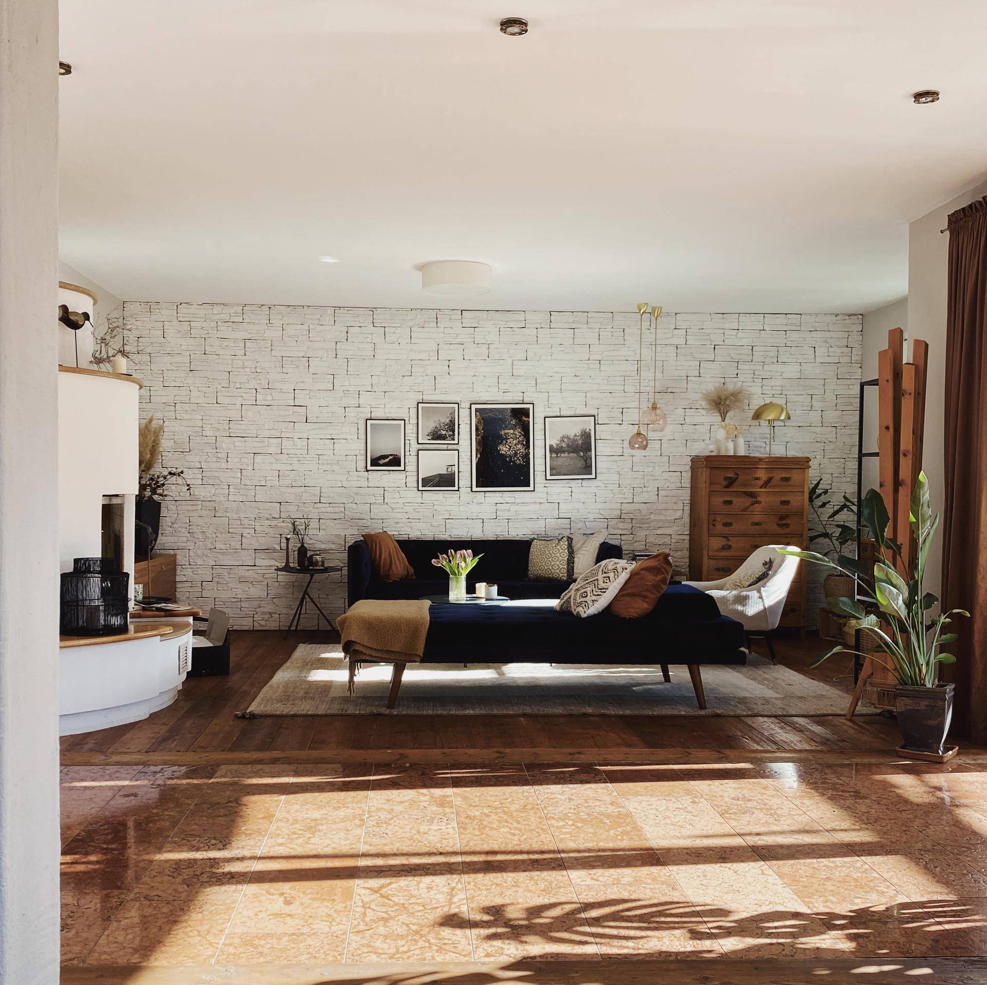 Helles Wohnzimmer mit Holzboden, moderner Einrichtung und dekorativer Ziegelwand.