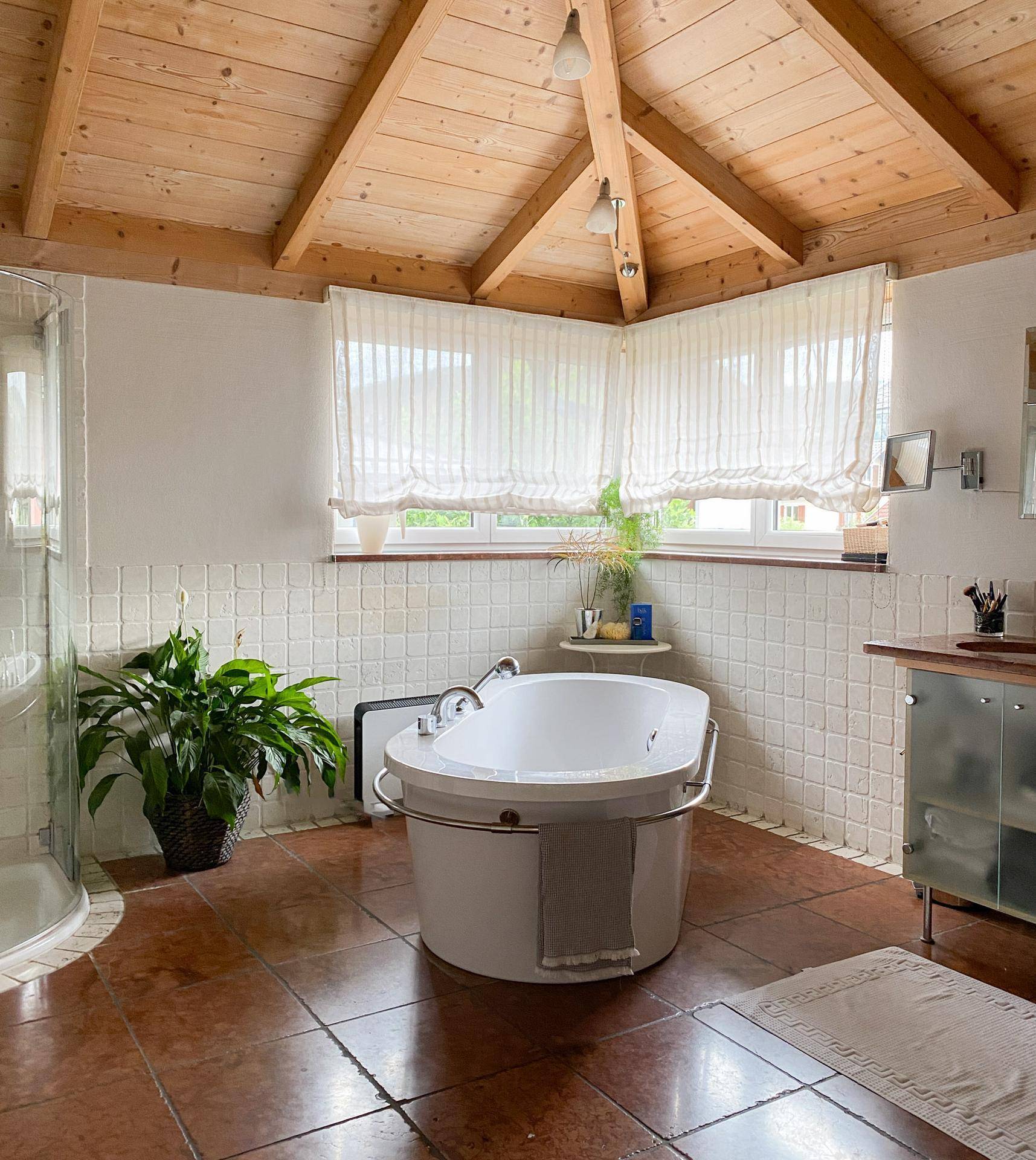 Geräumiges Badezimmer mit freistehender Badewanne, Dusche und Holzdachschrägen.