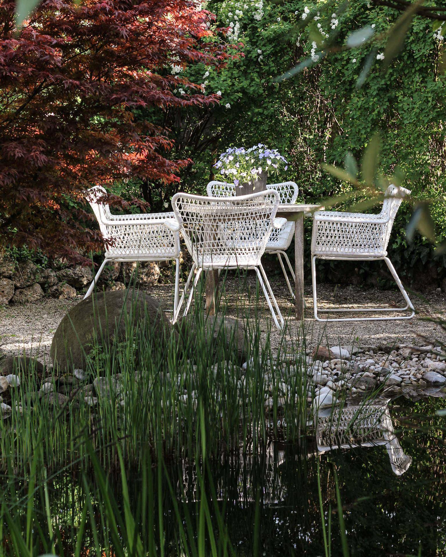 Idyllischer Gartenbereich mit Sitzgruppe, Teich und vielfältiger Bepflanzung für entspannte Stunden.
