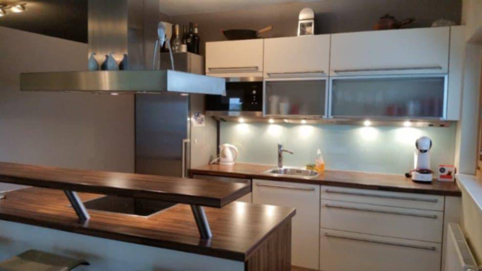 Moderne Küche mit hellen Schränken, Holzarbeitsplatten und einer praktischen Kücheninsel mit Bar.
