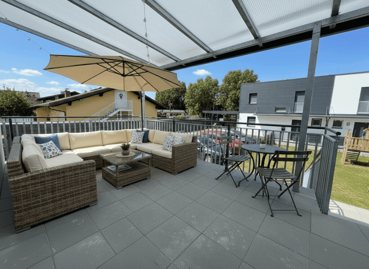 Geräumige überdachte Terrasse mit bequemen Loungemöbeln und Essbereich im Freien.