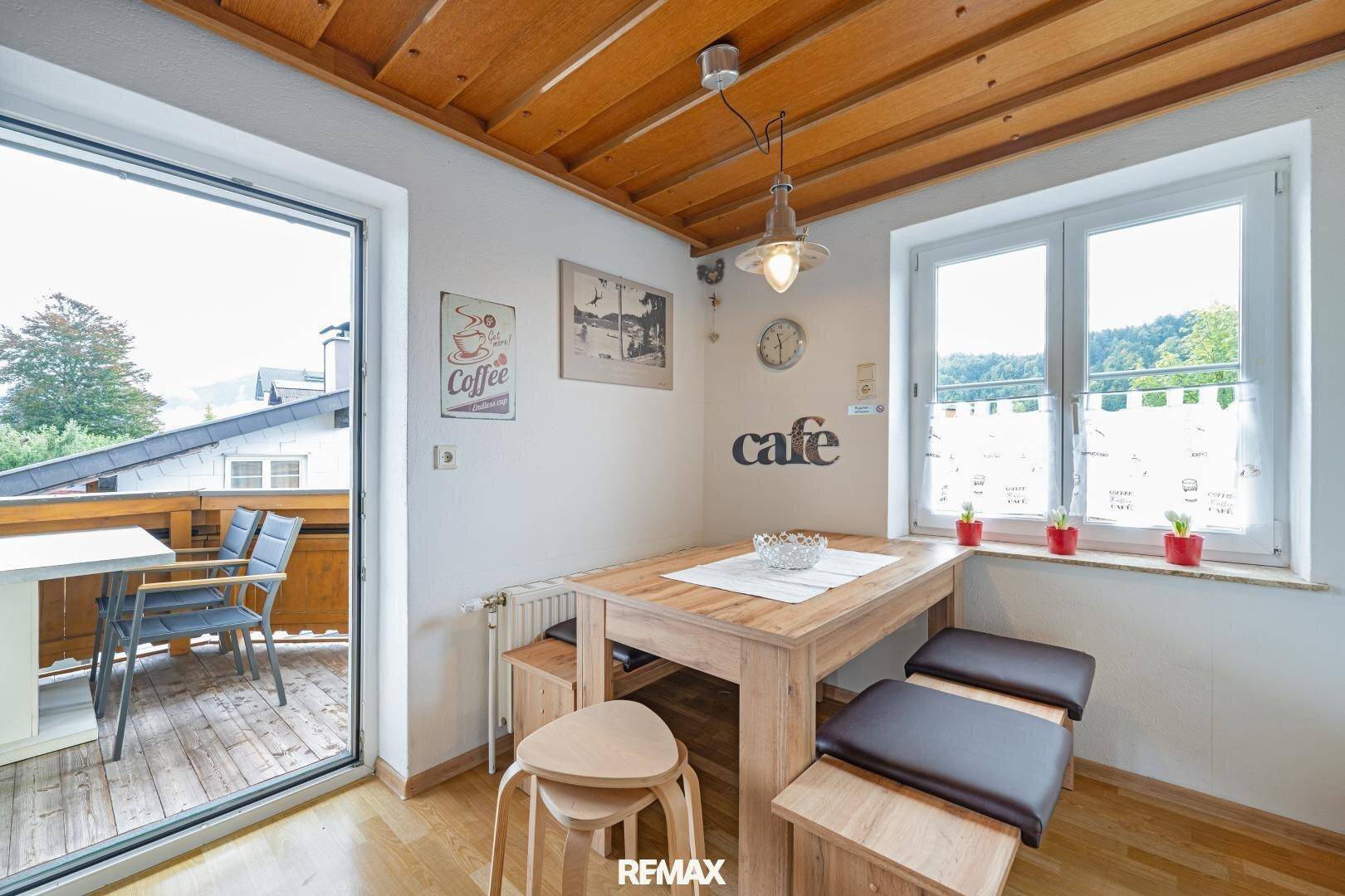 Heller Essbereich mit Holztisch, Holzbalkendecke und Zugang zum Balkon.