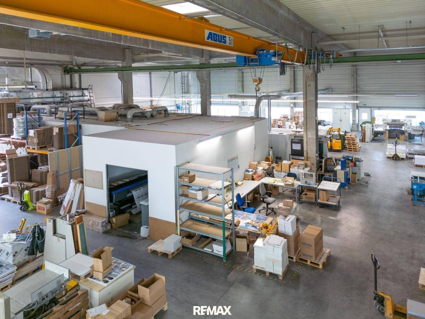 Produktionsbereich mit integriertem Büro, Maschinen und einem gelben Brückenkran.