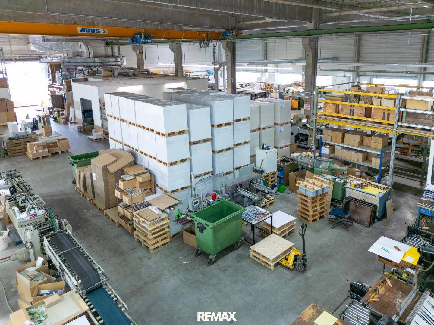 Industrielle Lagerhalle mit Produktionsmaschinen, Paletten und hohen Decken, bereit für den Betrieb.