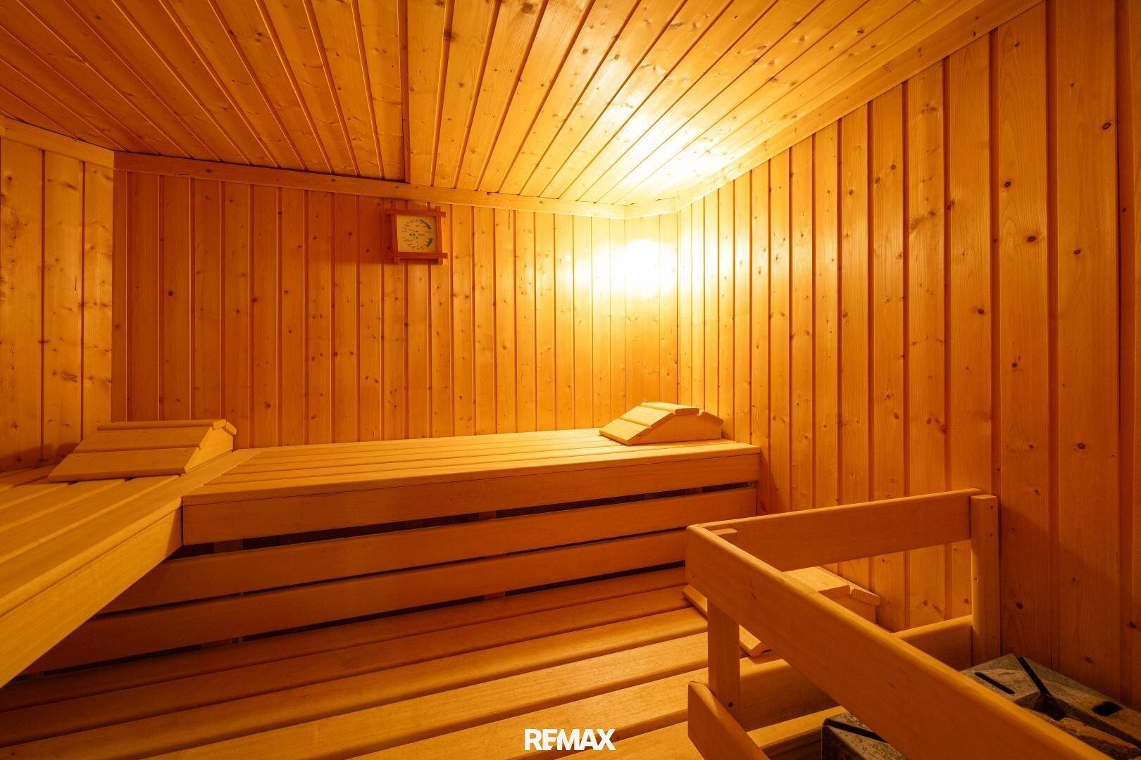 Traditionelle Holzsauna mit mehreren Bänken und warmer Beleuchtung für Entspannung.