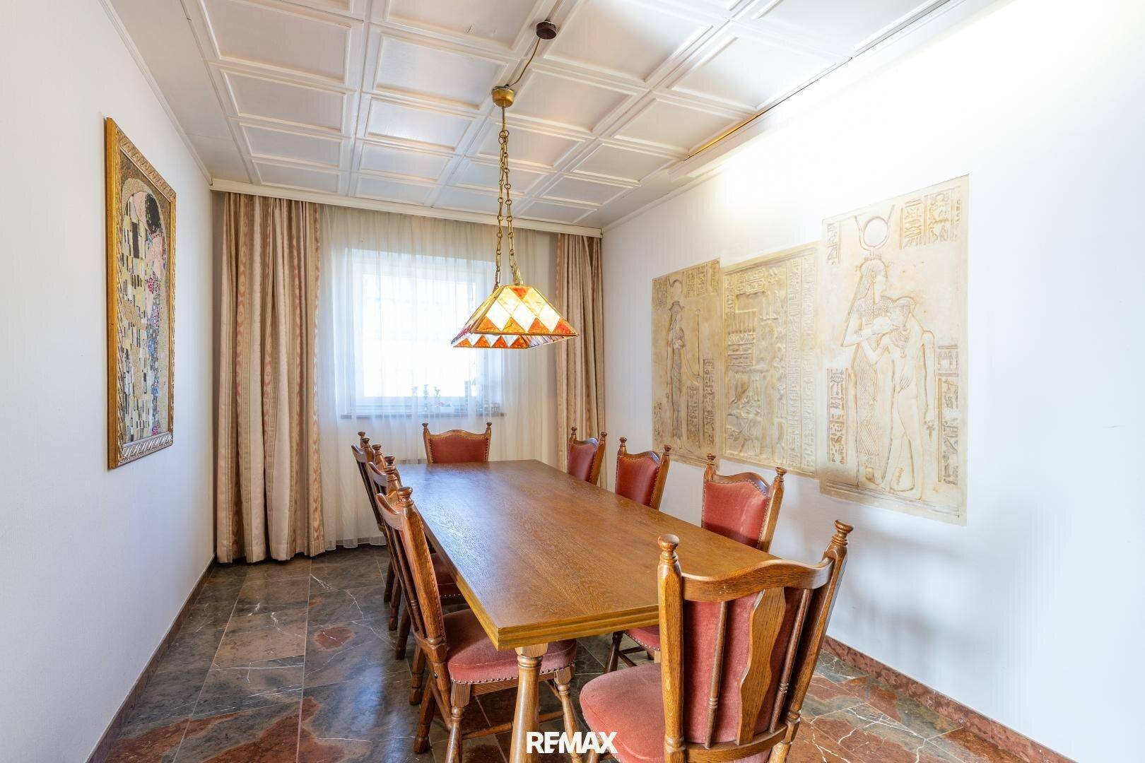 Klassisches Esszimmer mit großem Holztisch, traditionellen Stühlen und dekorativer Decke.