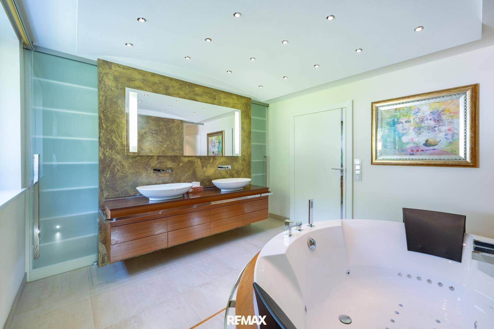 Elegantes Badezimmer mit Doppelwaschbecken, beleuchtetem Spiegel und Whirlpool.