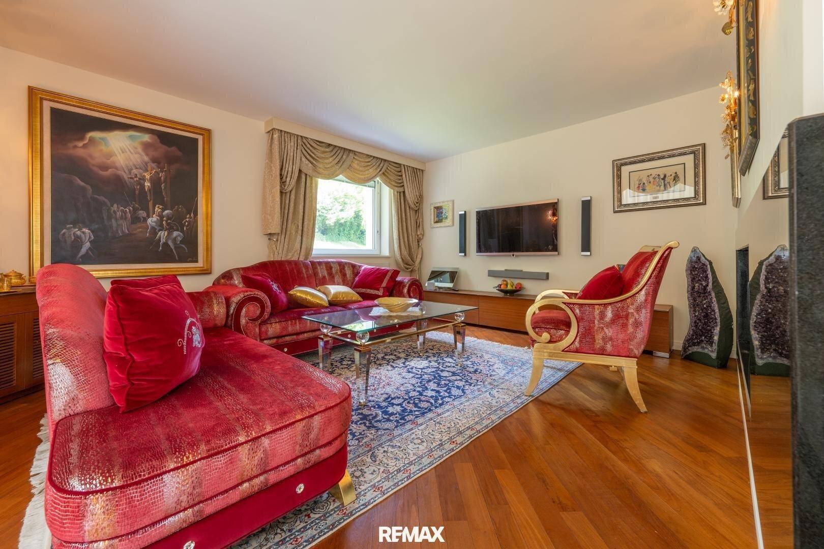 Elegantes Wohnzimmer mit rotem Sofa, Holzboden und großem Kunstwerk an der Wand.
