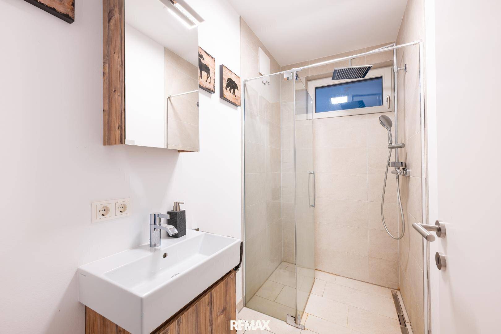 Kleineres Badezimmer mit begehbarer Dusche, modernem Waschbecken und Spiegelschrank.