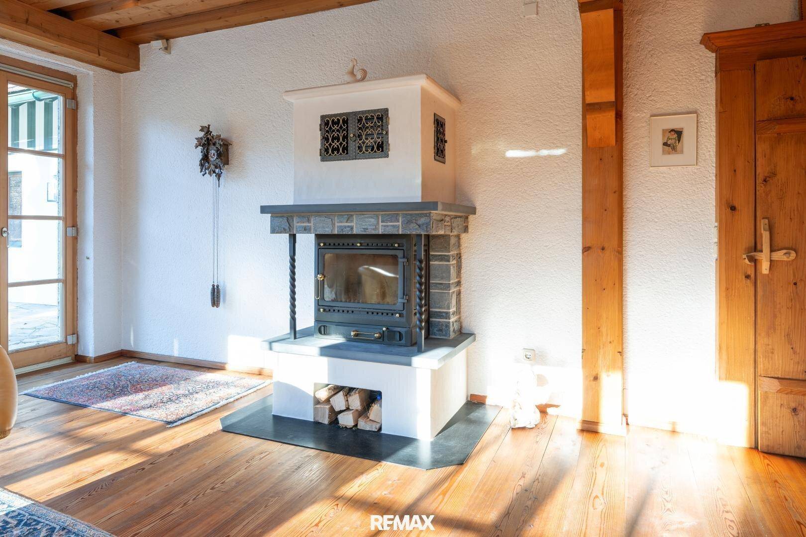 Traditioneller Kaminofen mit Holzscheitlagerung und rustikalen Details im Wohnbereich.