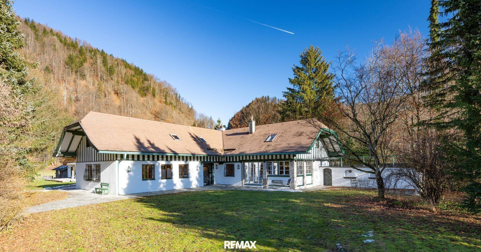 Charmantes Landhaus mit traditioneller Architektur, umgeben von grüner Natur und Bergen.