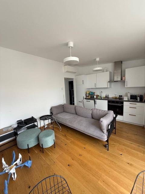 Offener Wohn-Ess-Küchenbereich mit Sofa, modernen Küchenschränken und Holzboden.